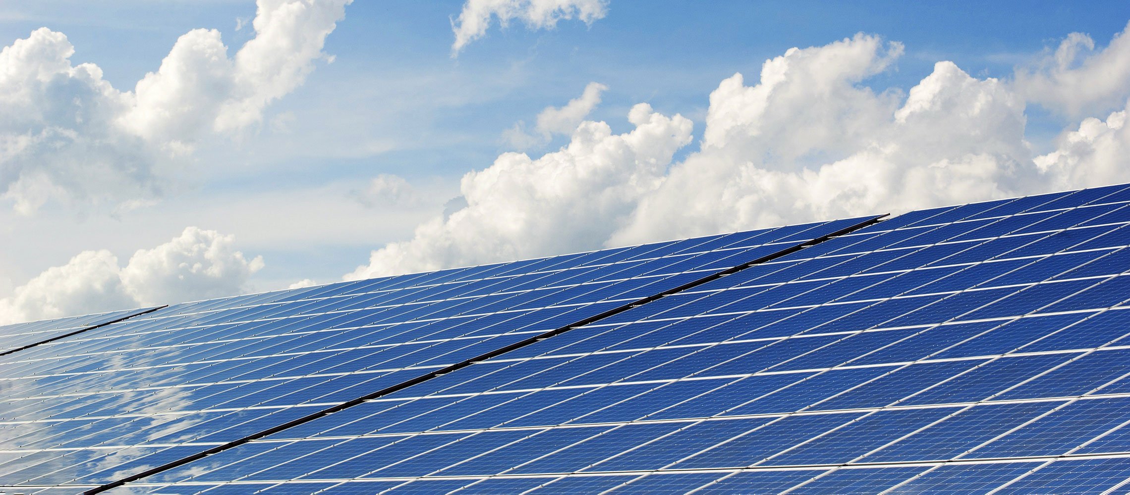 photo of solar PV panels on a roof with blue sky behind