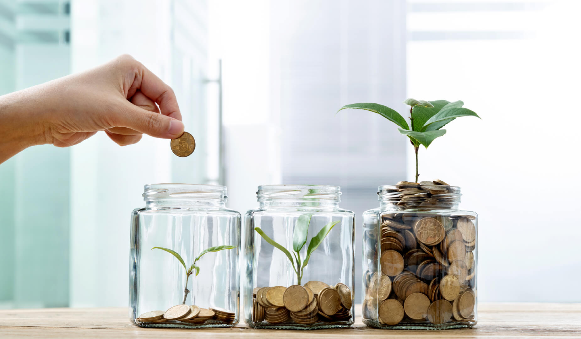 hand putting coins in a emergency savings jar