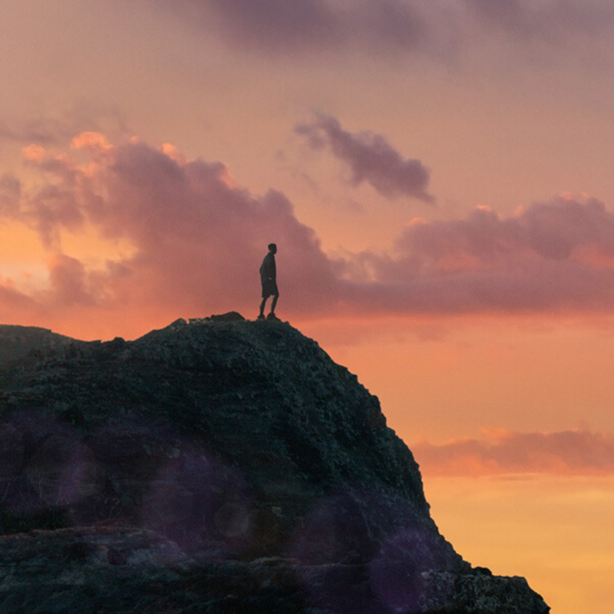 man standing on a oceanside cliff in sun